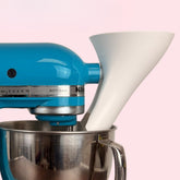 The Countess Flour Funnel attached to a stand mixer for mess-free ingredient addition.