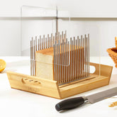 KHINYA bread slicer with boat-shaped tray catching crumbs and serving slices.