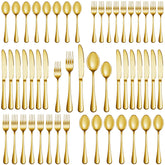 MUTNITT gold silverware set for 6 on a polished dinner table.