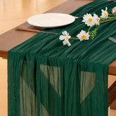 Socomi emerald green cheesecloth table runner draped for a wedding reception