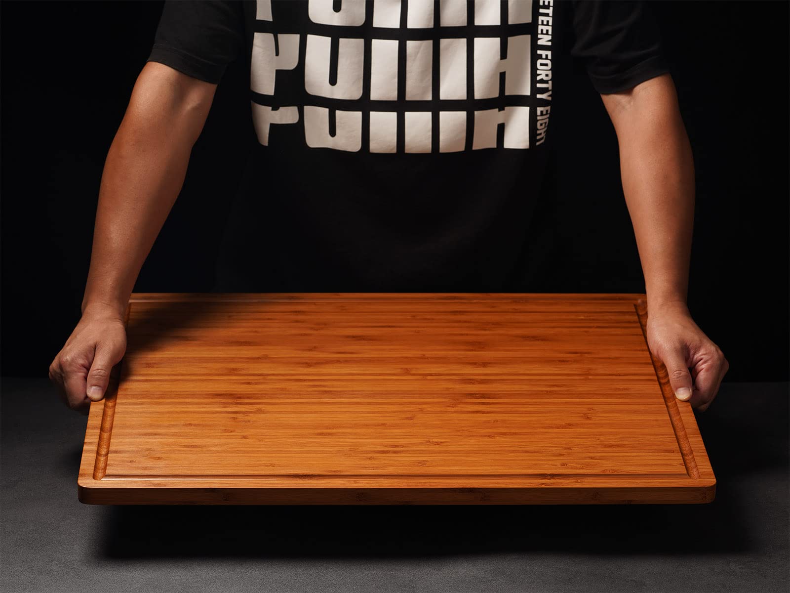 Allsum bamboo cutting board with handles close-up highlighting grip and slim profile.