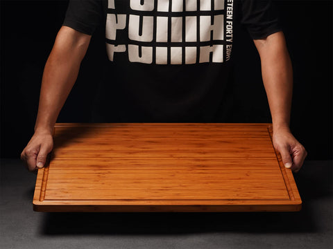 Allsum bamboo cutting board with handles close-up highlighting grip and slim profile.
