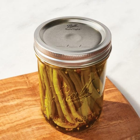 Ball wide mouth lids demonstrated on jars for preserving homemade foods.
