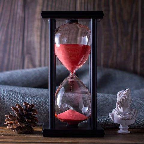 BELLAWARE red sand hourglass displayed on a desk and shelf.