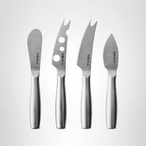 Hard cheese being cut with Boska knives on board