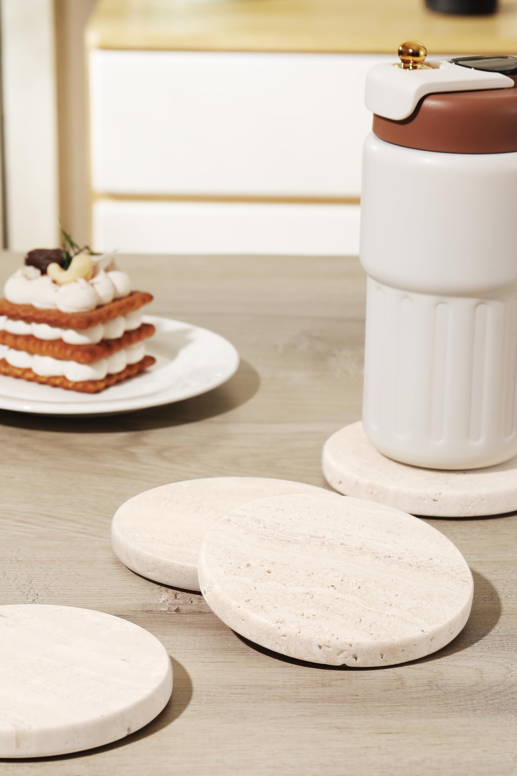 Set of four natural stone coasters by CHISELED ST DF SK on a table