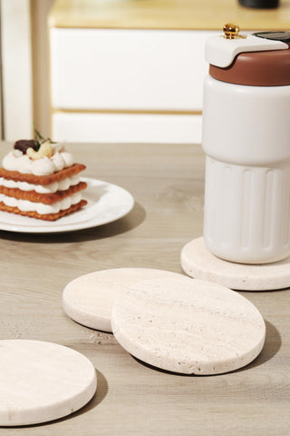 Set of four natural stone coasters by CHISELED ST DF SK on a table