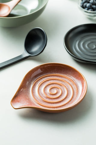 Cormomu spoon rest features reactive red glaze for decorative kitchen flair.