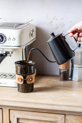 Cormomu mug with leather band provides grip and heat protection during travel.