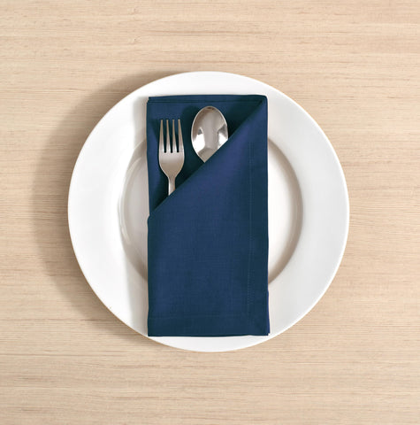 FINGERCRAFT navy napkins folded with mitered corners for a refined table.