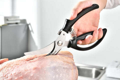 Gerior poultry shears in use slicing chicken, showcasing versatility