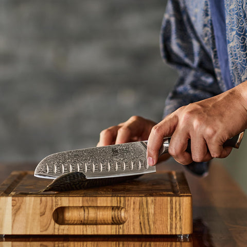 KYOKU Santoku Knife in use on a cutting board for chopping tasks.