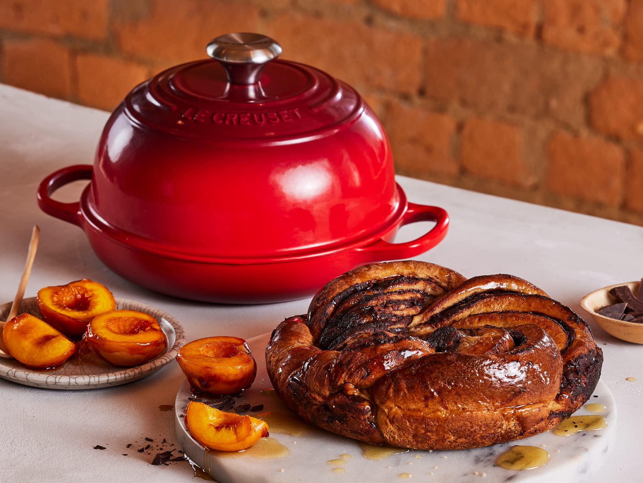 Le Creuset Bread Oven Cerise enamel finish resists staining and chipping for lasting beauty.