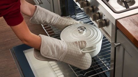 Le Creuset mitt highlights extended coverage and 550°F heat resistance.