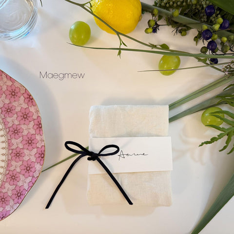 Maegmew place card tied to a napkin with velvet ribbon.