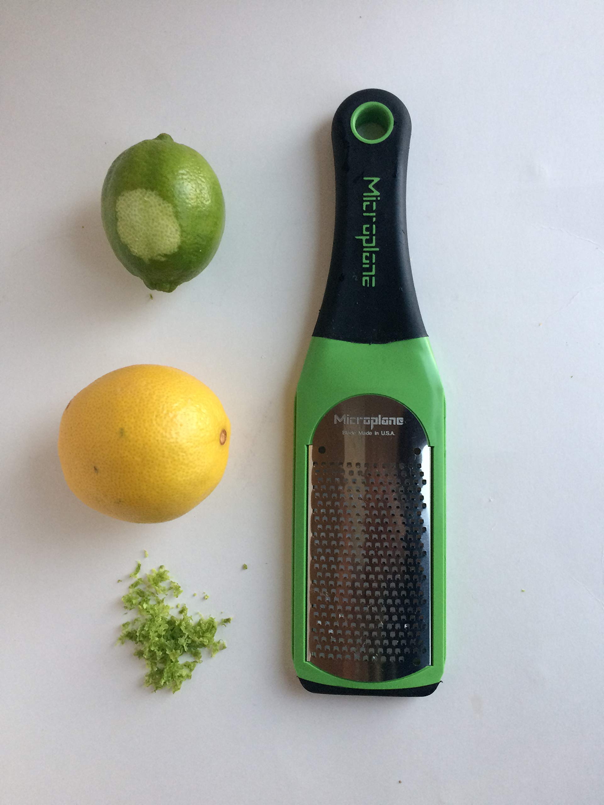 Microplane Artisan grater held in hand showing non-slip green handle.