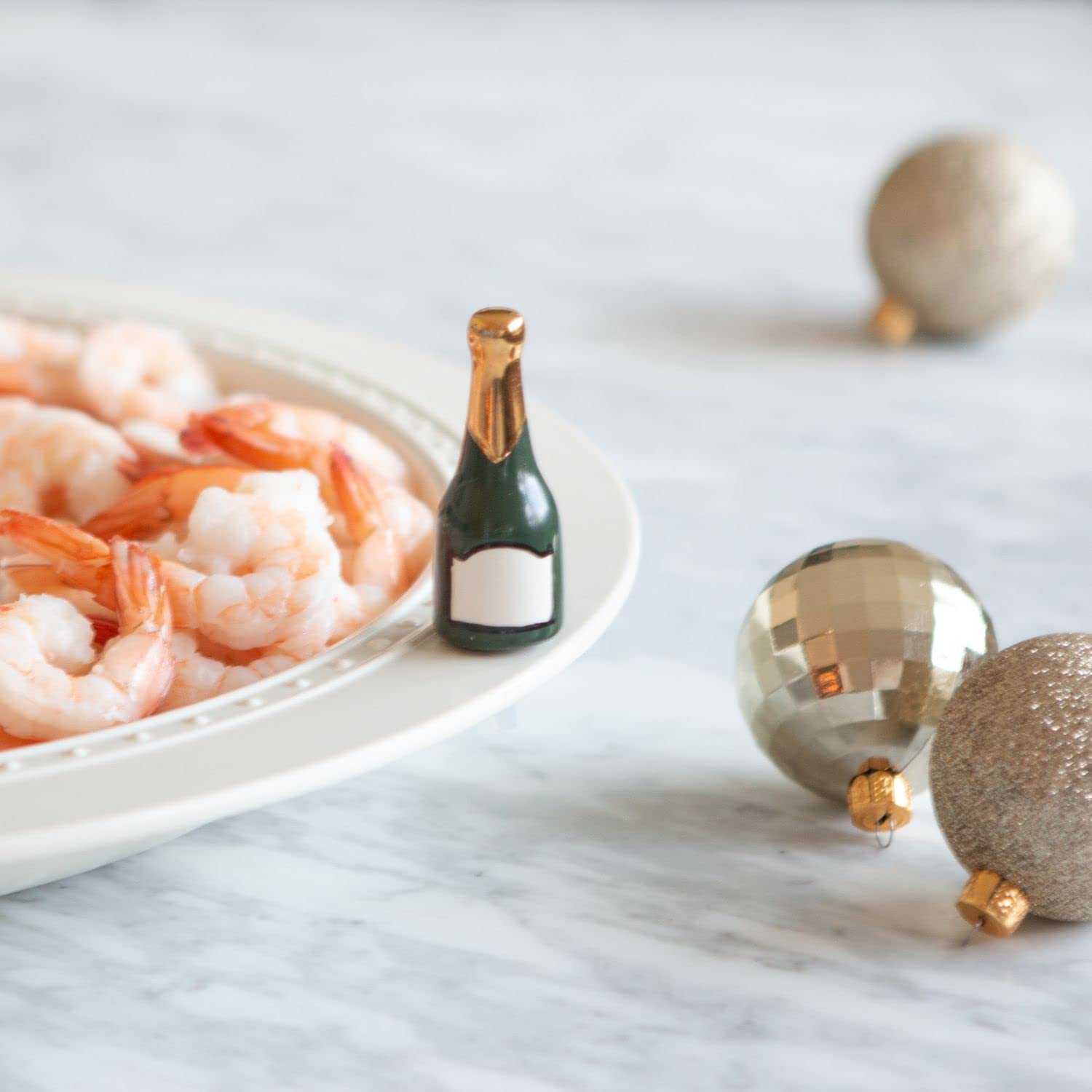 Nora Fleming champagne bottle mini on a dinner table adding sparkling flair