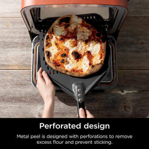 Ninja Woodfire perforated pizza peel in use inside a wood-fired oven for smooth transfer.