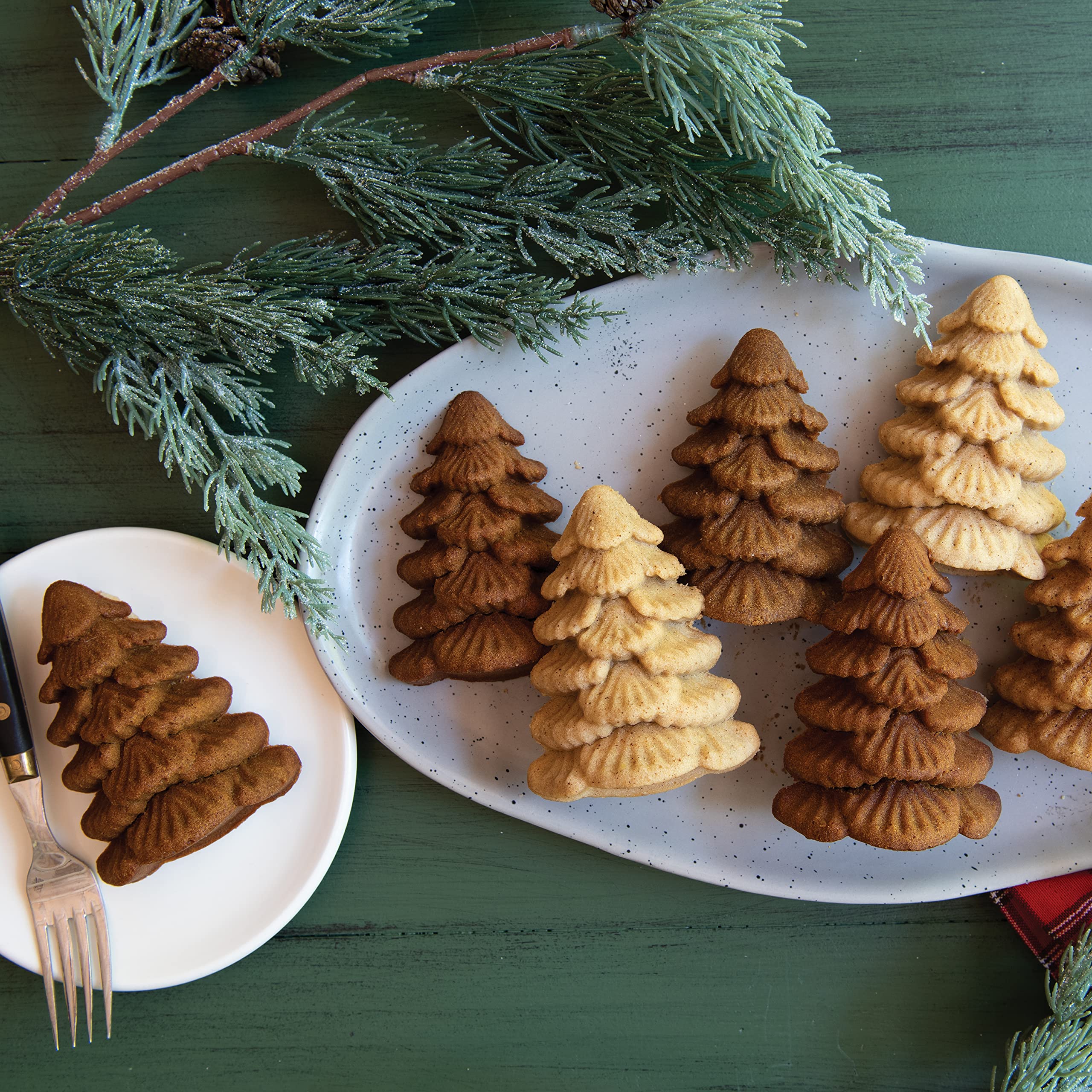 Nordic Ware Evergreen Cakelets in use, showcasing petite fir trees on a dessert tray.