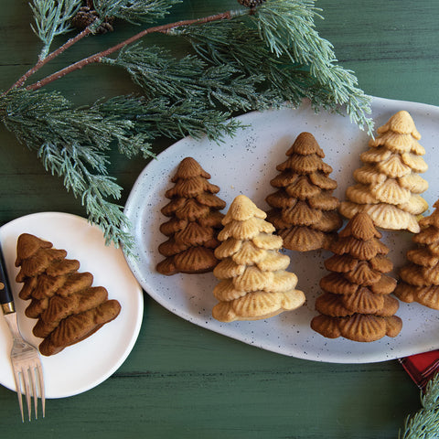 Nordic Ware Evergreen Cakelets in use, showcasing petite fir trees on a dessert tray.
