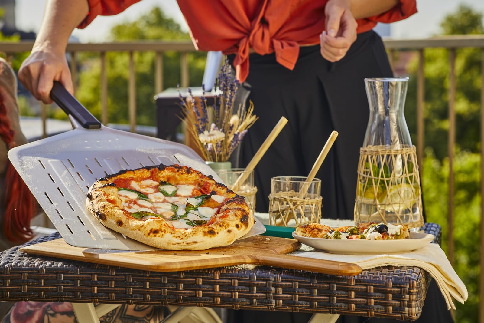 Ooni long-handle perforated pizza peel enables safe, distant reach from heat
