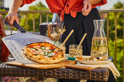 Ooni long-handle perforated pizza peel enables safe, distant reach from heat