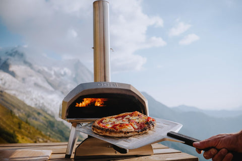 Ooni pizza peel in use demonstrates smooth dough transfer to oven.