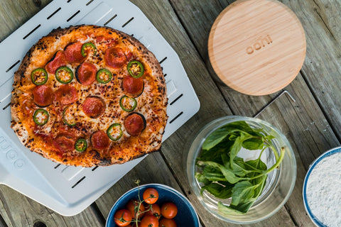 Ooni pizza peel slides a pizza toward the oven with ease