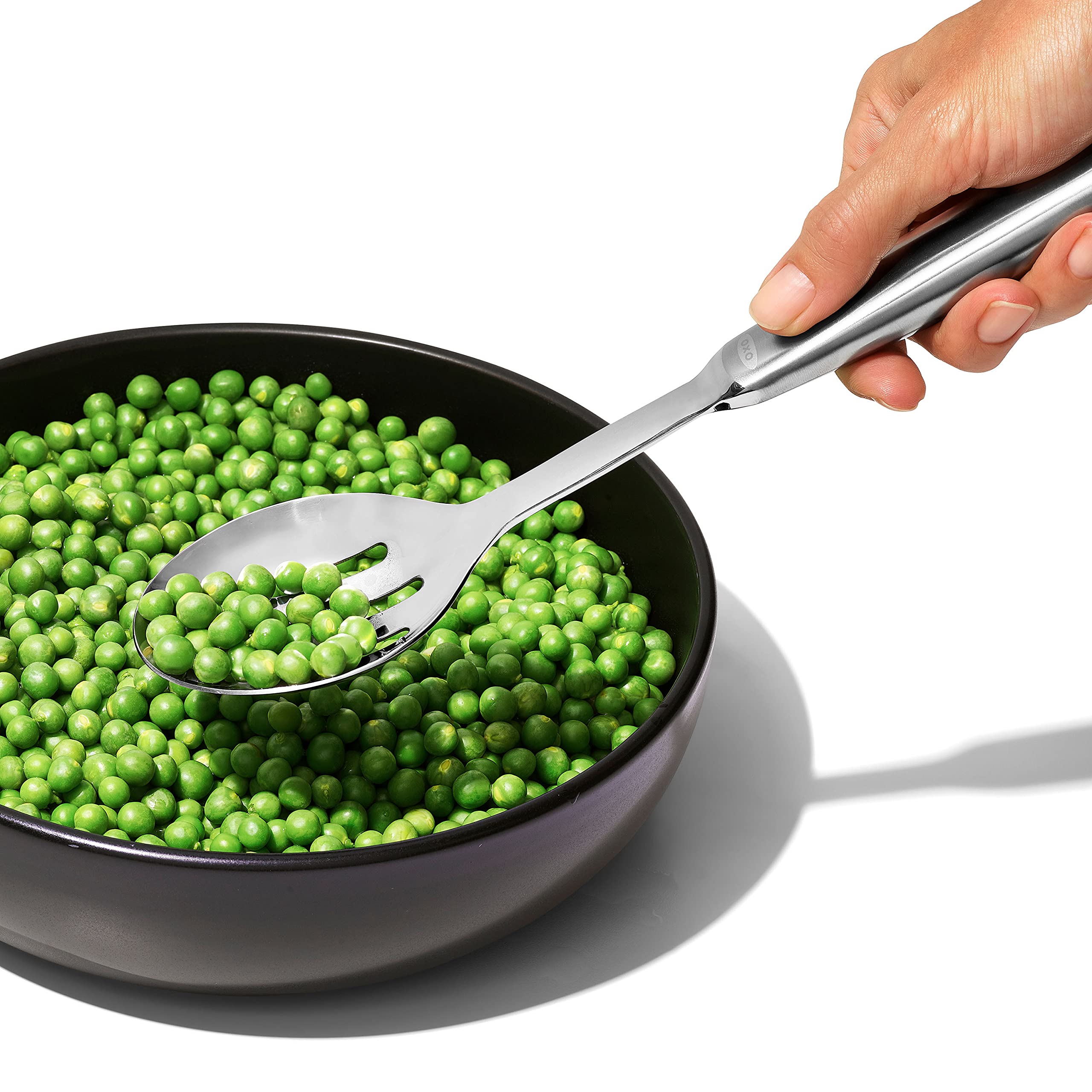 OXO steel slotted serving spoon mid-stir close-up, sturdy for thick stews