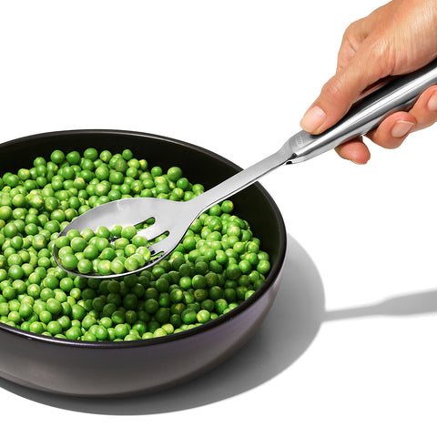 OXO steel slotted serving spoon mid-stir close-up, sturdy for thick stews