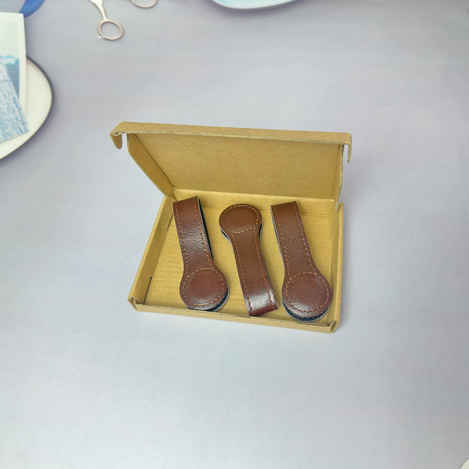 Prriudy brown leather clip attached to towels on a rack for neat storage