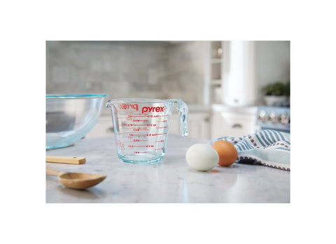 Pyrex measuring cup with red graphics, microwave safe for quick heating.