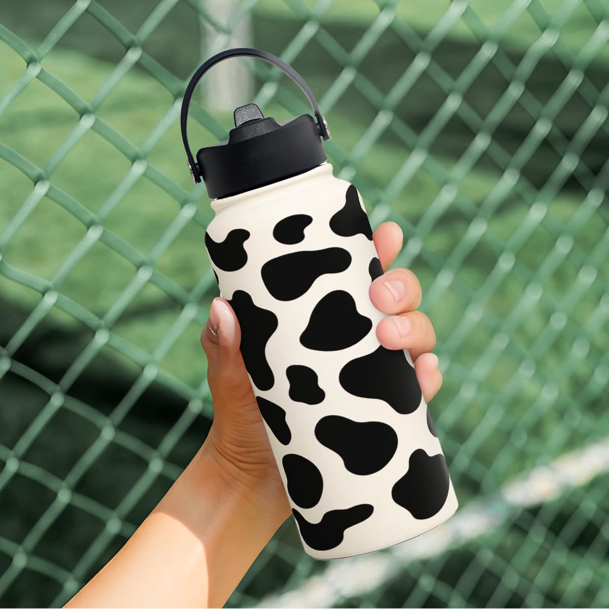 SANDJEST Cow Print Bottle 32oz in use at sports events or trips.