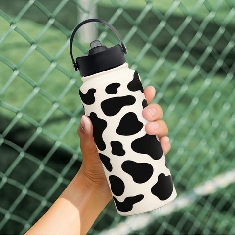 SANDJEST Cow Print Bottle 32oz in use at sports events or trips.