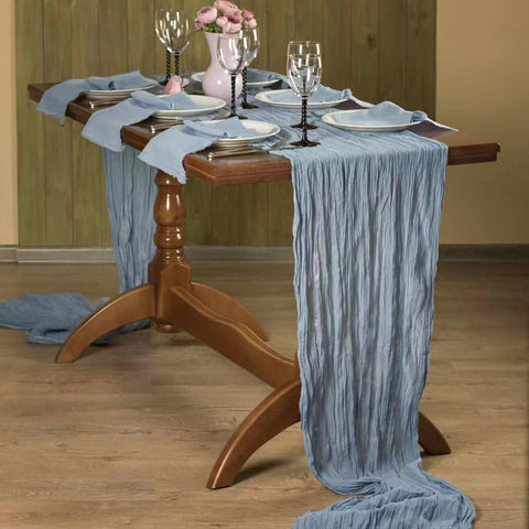 Seveups dusty blue cheesecloth table runner on wedding table creating delicate drape.