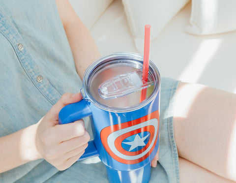 Silver Buffalo Captain America shield tumbler beside cup holder, travel-friendly.