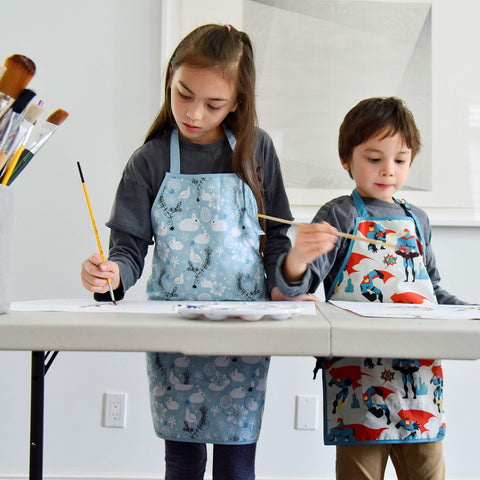 Urban Infant Little Helper apron featuring superheroes, encourages creative projects and cooking tasks.