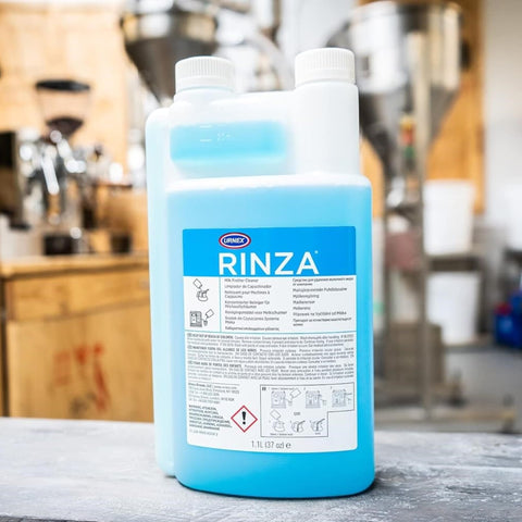 Urnex Rinza steel pitcher cleaner removing milk residue from metal surfaces.