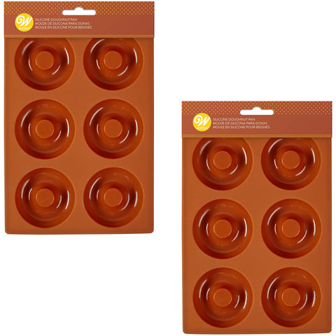 Wilton donut pans shown cooling donuts on a rack for even setting.