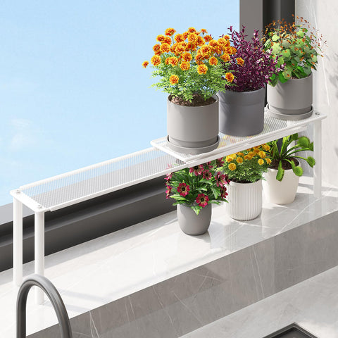 WOCHUANGSI expandable window shelf displays plants on a sunlit sill for space-saving display.
